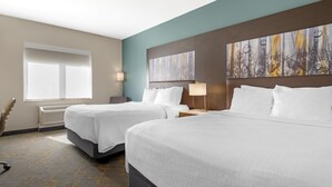 A hotel room with two beds, a large abstract painting on the wall, a window with blinds, and a radiator. - Best Western Plus Isanti (Isanti)