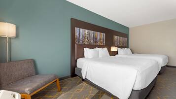 A hotel room with two beds, a sofa, a lamp, and abstract wall art.