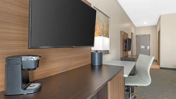 Une chambre d’hôtel équipée d’un téléviseur à écran plat, d’une machine à café, d’un bureau avec une chaise et d’une lampe.