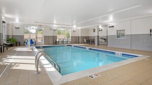 A swimming pool with a tiled deck, a clock, and a seating area with tables and chairs. - Best Western Plus Isanti (Isanti)