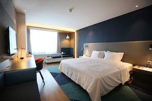 A modern hotel room with a large bed, a desk with a chair, a television, and a window with curtains. - Holiday Inn Express Chengdu North Railway Station by IHG (Chengdu)