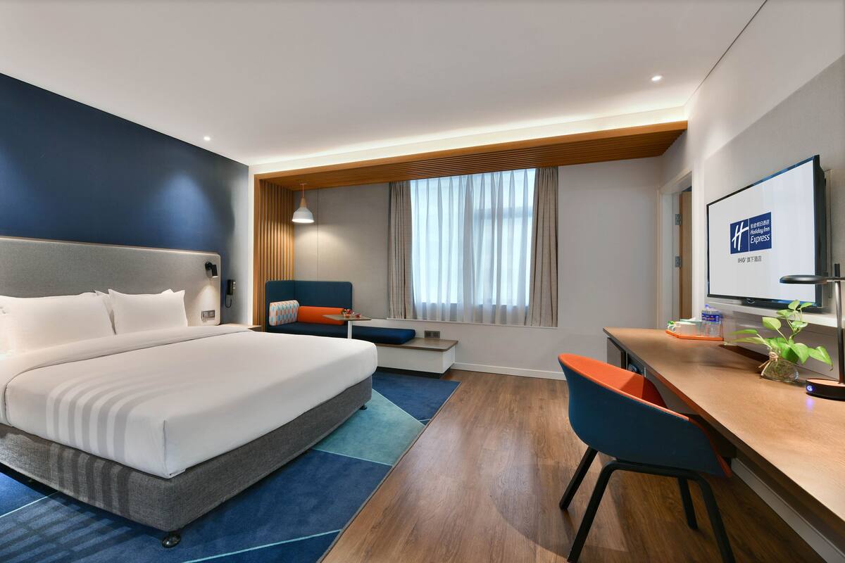 Una habitación de hotel moderna con una cama grande, un escritorio y una zona de estar.