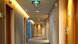 Un pasillo de hotel con alfombra estampada, paredes de madera y puertas a ambos lados.