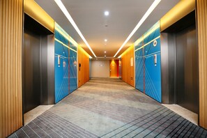 Eine moderne Elevator-Eingangsbereich mit gemustertem Teppich, Holzvertäfelung und blauen geometrischen Wandmustern.