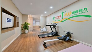 Habitación de hotel con una caminadora, bicicleta estática y un televisor montado en la pared.