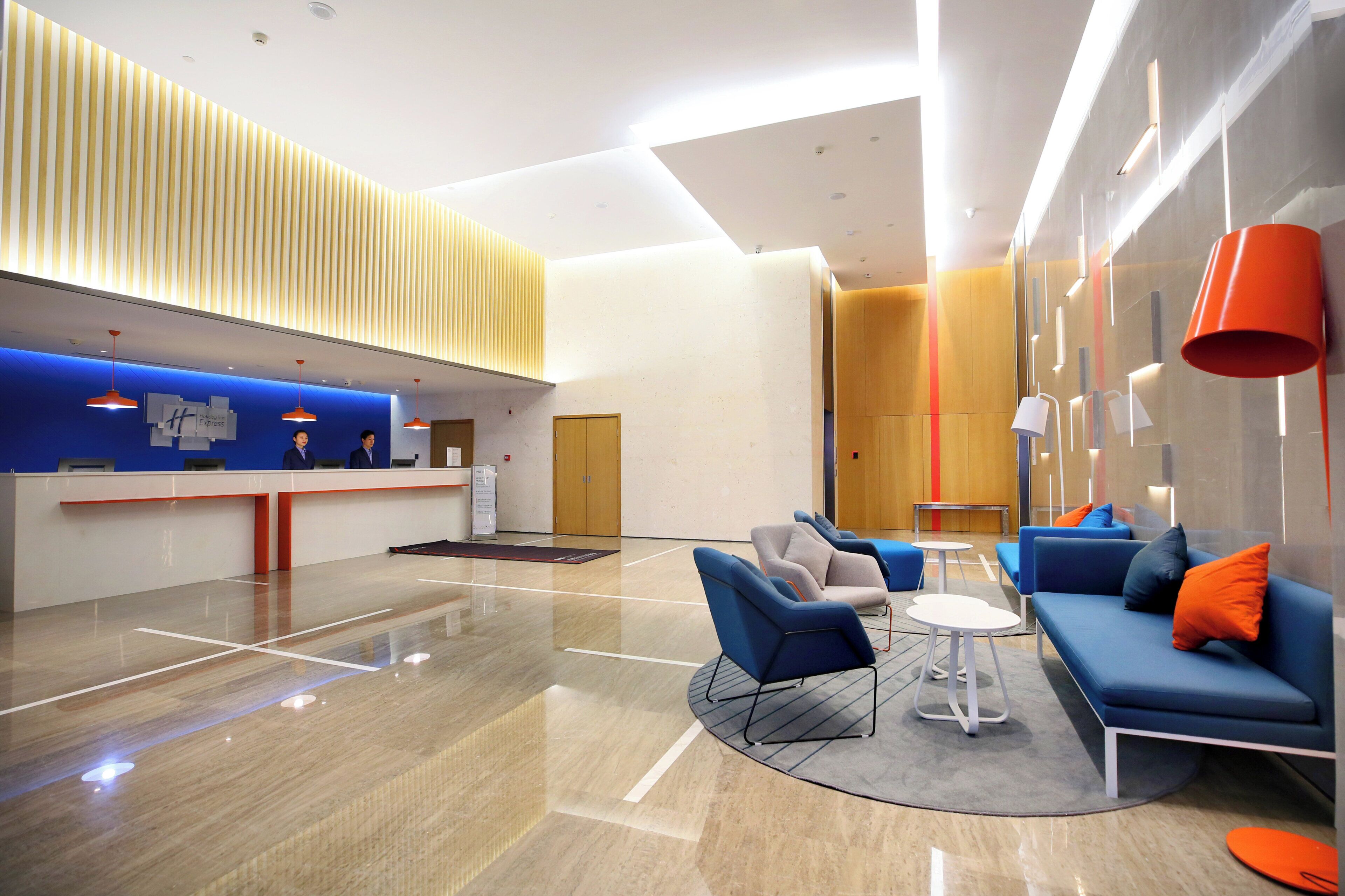 Rebost d'hotel modern amb taulell d'adreça, zona de seients i paret de fusta amb llistons verticals.