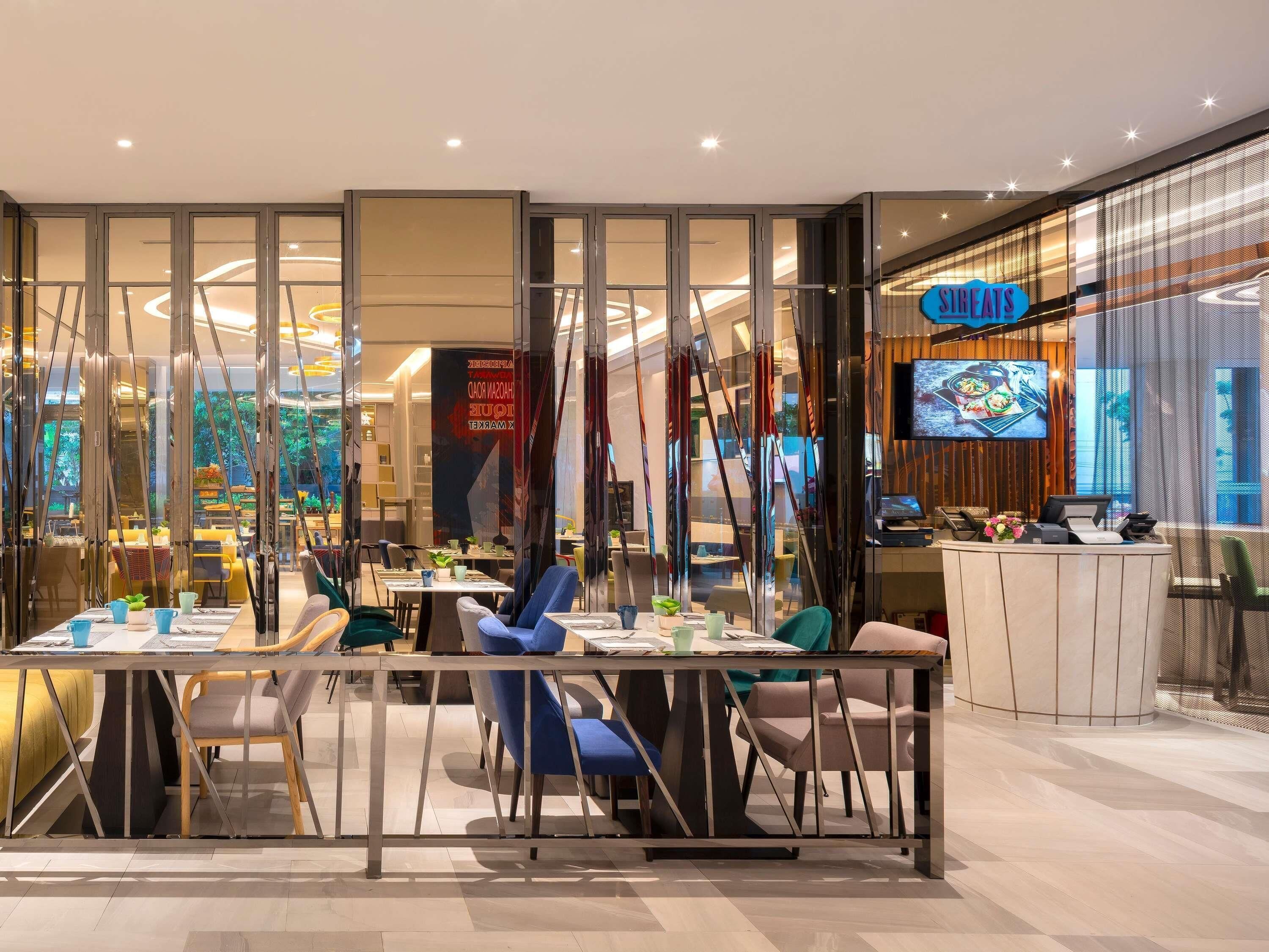 Un restaurant moderne doté d’une paroi en verre, d’un comptoir d’accueil et d’un écran de télévision.