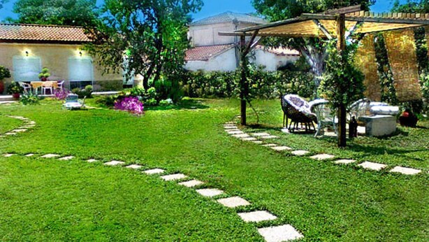 Ein gepflegter Garten mit Terrasse, Gartenmöbeln und einer Pergola.