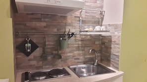 A compact kitchen with a built-in stove, a sink, and a hanging utensil rack. - Le Stanze Di Angela (Naples)