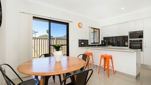 A modern kitchen with white cabinets, black and white tiles, and two built-in ovens. - Villa Mare - 4 Mins to Beach (Culburra Beach)
