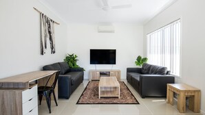 A modern living room with a flat-screen TV, two sofas, a coffee table, and a dining area with a wooden table and chairs. - Villa Mare - 4 Mins to Beach (Culburra Beach)