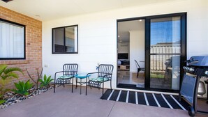 A patio with two chairs and a small table, a barbecue grill, and a sliding glass door leading to a backyard. - Villa Mare - 4 Mins to Beach (Culburra Beach)