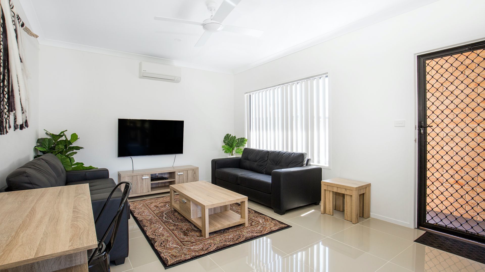 Uma sala de estar moderna com televisão de tela plana, sofá, mesa de centro e uma mesinha lateral.
