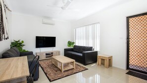 Een moderne woonkamer met een flatscreen televisie, een bank, een salontafel en een bijzettafeltje.