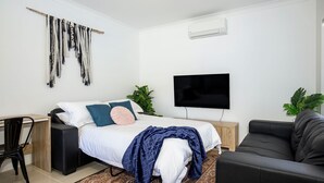 A modern bedroom with a bed, a desk, a TV, and a sofa. - Villa Mare - 4 Mins to Beach (Culburra Beach)