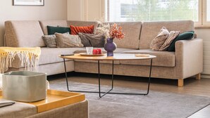 A living room with a sofa, a coffee table, a lamp, and a window with blinds.