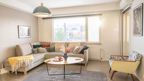 A modern living room with a sofa, coffee table, and a patterned armchair.