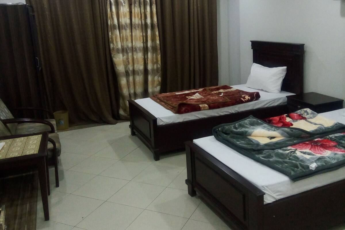 A hotel room with two beds, a desk, and a chair.