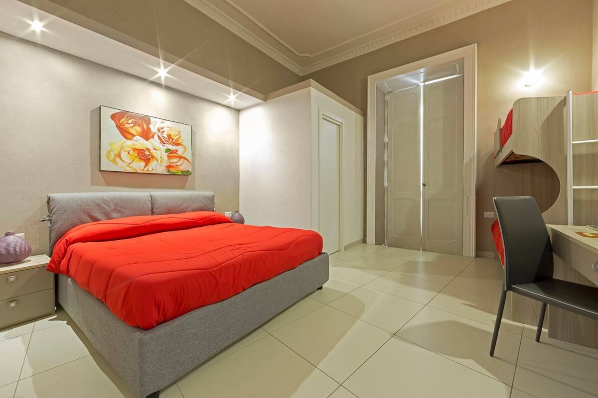 Un dormitorio moderno con cama, mesita de noche y escritorio con silla.