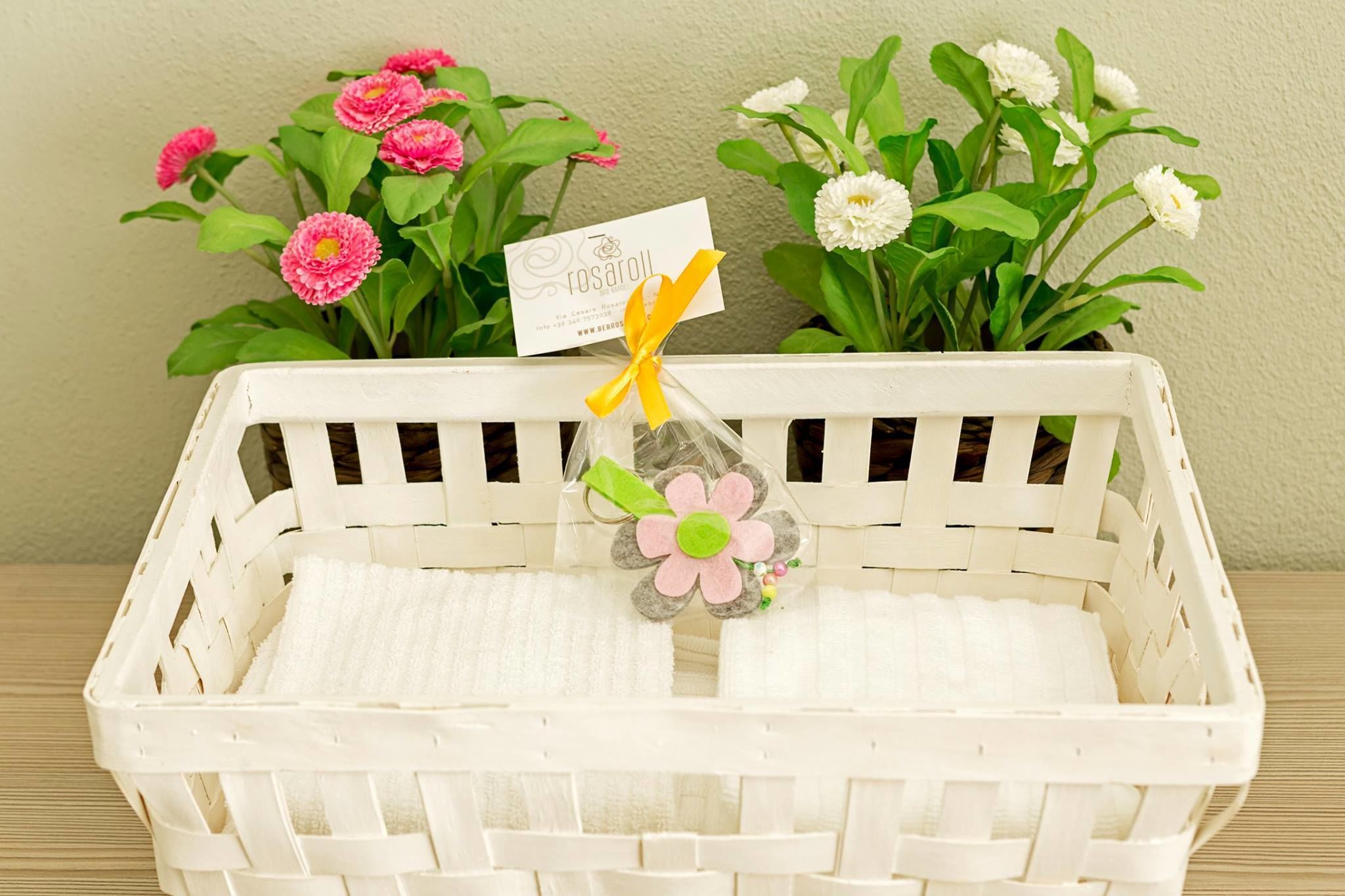 Un panier en osier blanc, agrémenté d’une étiquette et d’une fleur décorative.