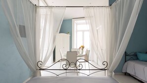 Un dormitorio con cama a dosel, una zona de comedor con mesa y sillas, y vistas al exterior.