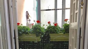 Un pasillo estrecho con un muro de azulejos, una planta en maceta y una pequeña macera en el suelo.