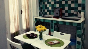 Una cocina con salpicadero a cuadros, una cafetera y un florero con flores amarillas sobre la encimera.
