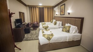 Une chambre d’hôtel avec deux lits, un bureau avec un ordinateur, une chaise et un téléviseur.