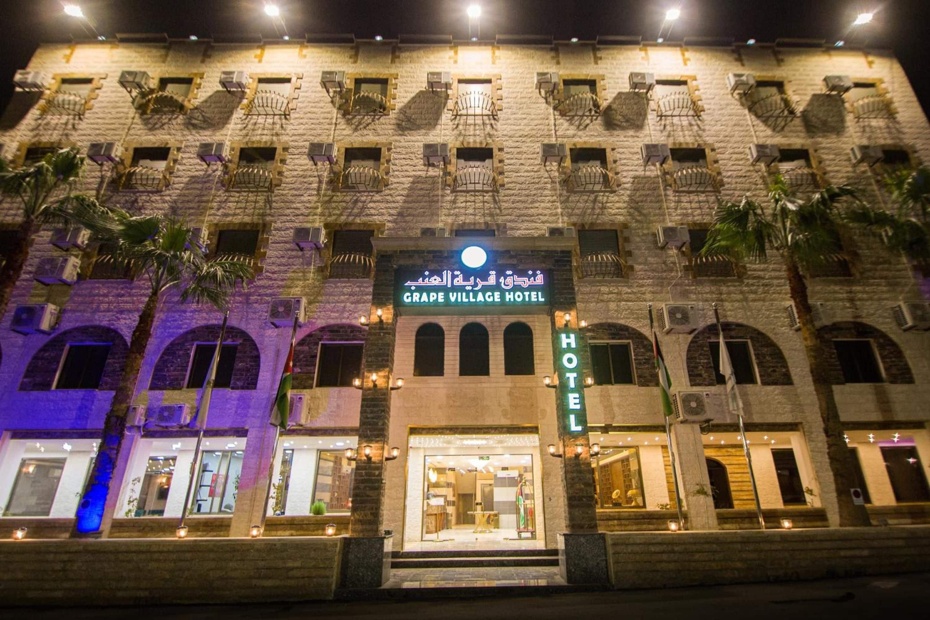 A hotel with a stone facade, multiple balconies, and a prominent sign indicating it's the Grape Village Hotel.
