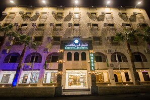 A hotel with a stone facade, multiple balconies, and a prominent sign indicating it's the Grape Village Hotel. - Grape Village Hotel (Amman)