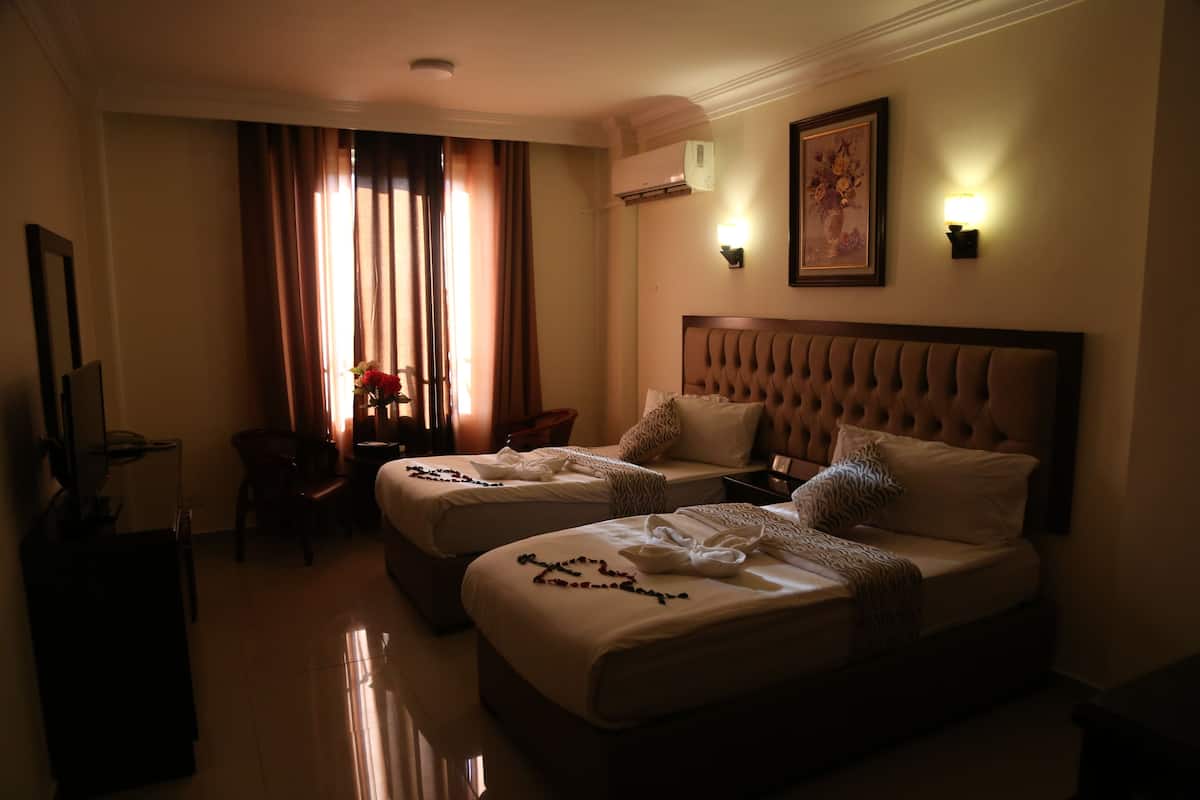 A hotel room with two beds, a desk, and a chair.