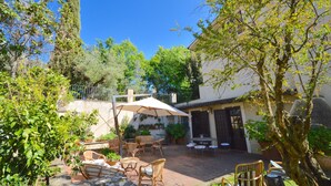 Une terrasse extérieure aménagée avec des meubles en osier, une table et un grand parasol.