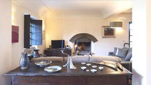 Un salon chaleureux avec une cheminée, un canapé, une table basse et un téléviseur.