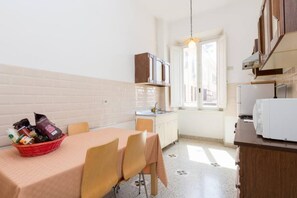 A compact kitchen with a dining table, chairs, a refrigerator, and a window. - Vatican Comfortable Sunny Apartment (Rome)