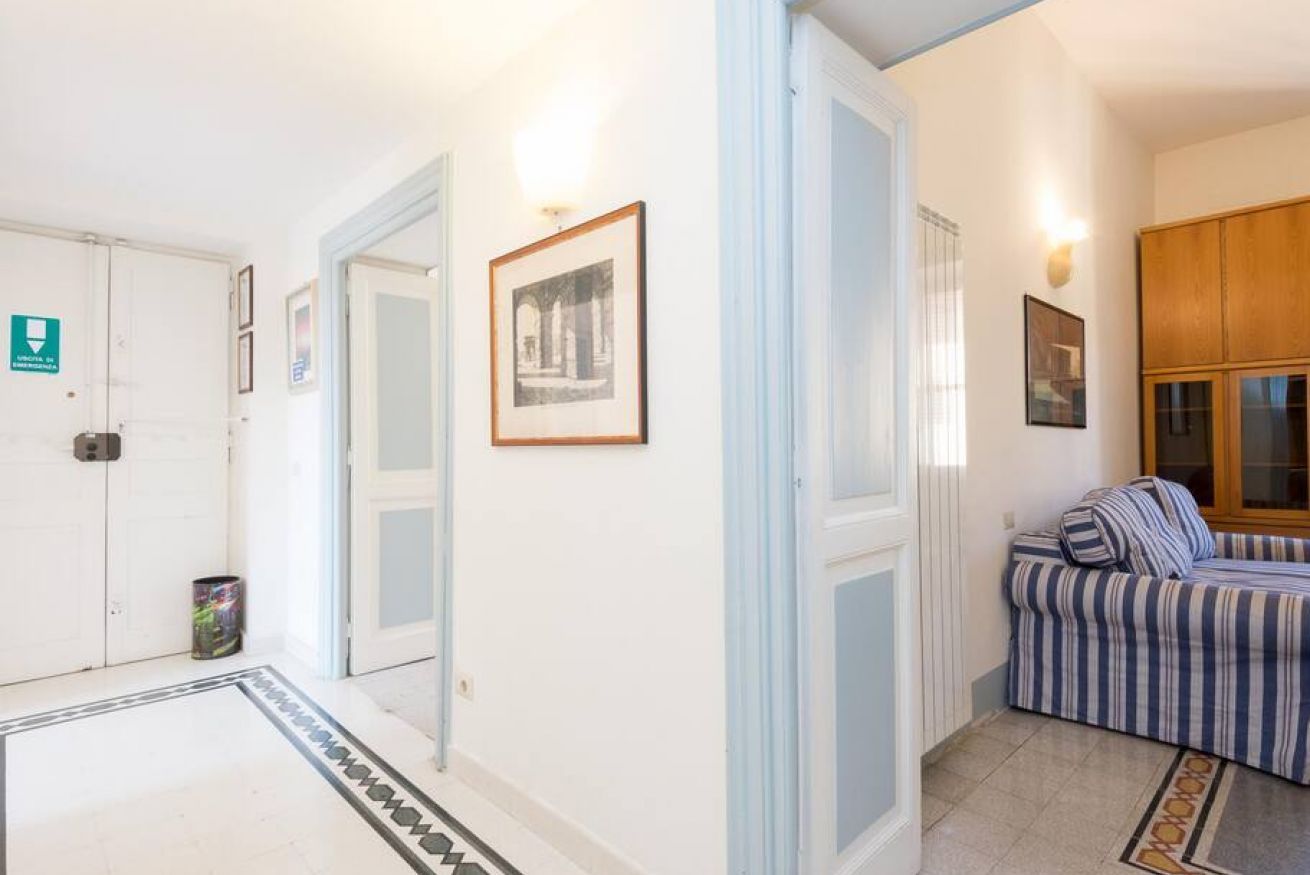 A hallway with a white door, a framed picture on the wall, a striped sofa, and a patterned rug.