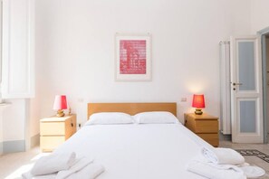 A hotel room with a bed, two bedside tables with lamps, a framed picture on the wall, and a door. - Vatican Comfortable Sunny Apartment (Rome)