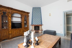 A living room with a fireplace, a wooden cabinet, a television, and a patterned rug. - Vatican Comfortable Sunny Apartment (Rome)