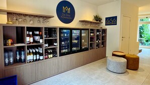 Un espace bar avec des étagères remplies de bouteilles et de verres, un logo sur le mur et une porte donnant sur l’extérieur.