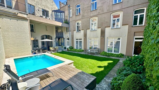 Un immeuble résidentiel doté d’une piscine, d’une terrasse en bois et d’une pelouse bien entretenue.