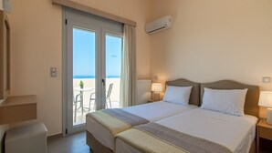 A hotel room with two beds, a balcony with a table and chairs, and an air conditioning unit.