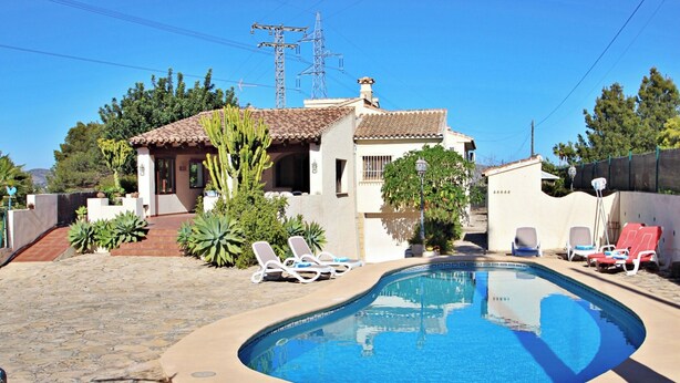 A swimming pool with lounge chairs, a house with a tiled roof, and a clear blue sky. - El Ventorrillo - holiday home with stunning views and private pool in Benissa (Benissa)