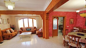 A spacious living room with a wooden ceiling, a dining area with a table and chairs, and a large window providing natural light. - El Ventorrillo - holiday home with stunning views and private pool in Benissa (Benissa)