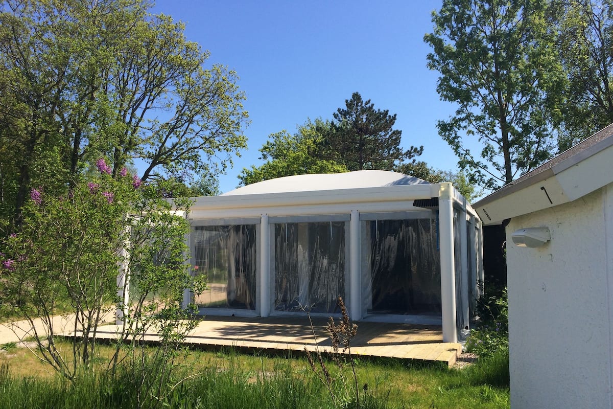 A covered patio area with a view of the surrounding garden and trees.