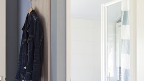 A bathroom with a shower, a sink, and a mirror. There is a wooden wall and a blue wall. - Strand 49 Camping & Glamping (Sint Maartensbrug)