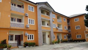 A multi-story building with numbered balconies, air conditioning units, and potted plants. - Waterworld Apartments (Ibadan)