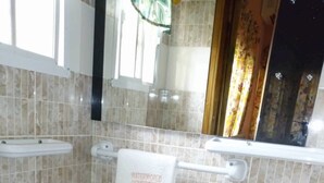 A bathroom with a toilet, sink, and a towel rack with a towel hanging on it. - Waterworld Apartments (Ibadan)