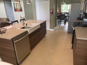A modern kitchen with a central island, a dishwasher, and a dining area with chairs and a table.