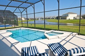Une piscine avec des chaises longues, un jacuzzi et une vue sur un quartier résidentiel.