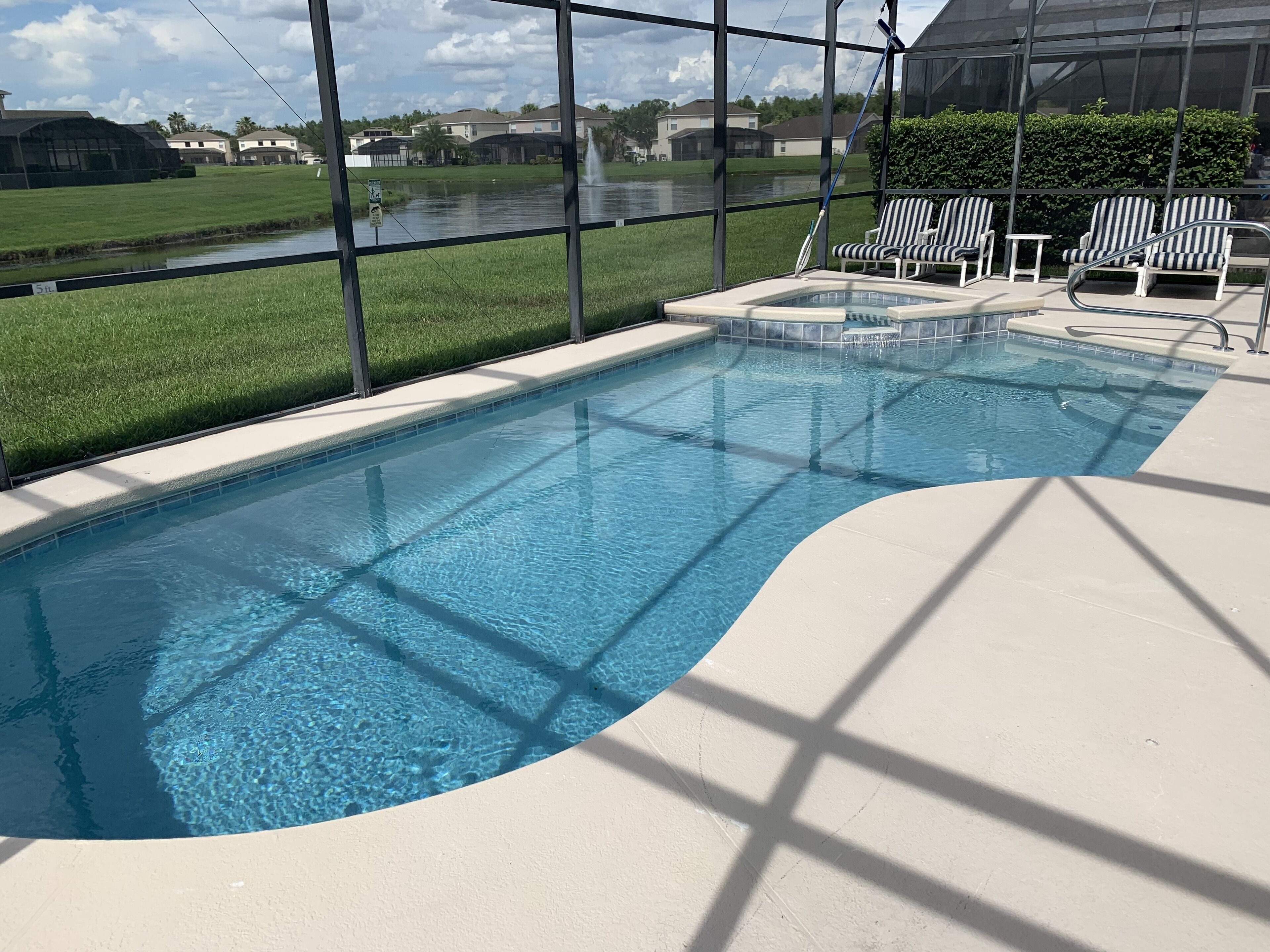 Una piscina con agua azul cristalina, rodeada por una terraza blanca y sillas de descanso.