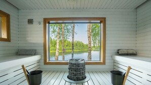 Een sauna met een groot raam, houten banken en twee emmers.